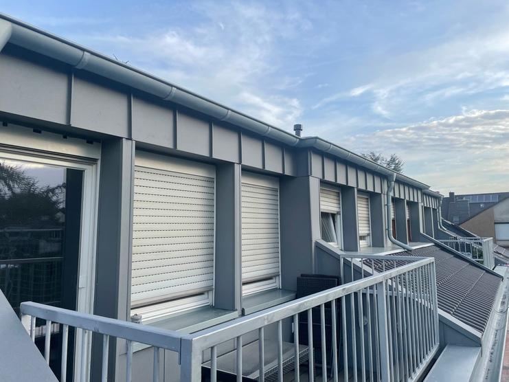 Moderne Bauklempnerei-Arbeiten an einem Stadthaus Elegante Metallverkleidung und Fensterläden an einem Stadthaus, fachmännisch installiert von einer Bauklempnerei bei Dämmerung.