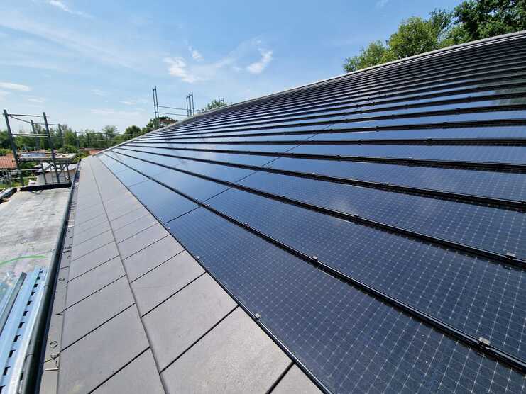 Installation von Solarmodulen auf einem Dach durch eine Bauklempnerei Fachgerechte Montage von Solarmodulen auf einem geneigten Dach durch eine professionelle Bauklempnerei bei sonnigem Wetter.