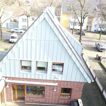 Giebelverkleidung mit Metallpaneelen Wohnhaus mit roter Klinkerfassade und moderner Giebelverkleidung aus langlebigem Metall.
