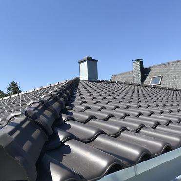 Neues Ziegeldach mit Kamin Dunkles Dach mit neuen Ziegeln, modernem Kamin und Gaube, professionell eingedeckt.