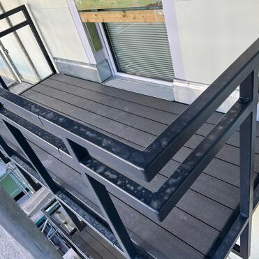 Neuer Balkon mit Geländer Schmaler Balkon mit stabilem schwarzen Metallgeländer und dunklem Bodenbelag.