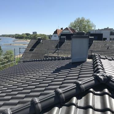 Dachsanierung mit Kamin am Rhein Frisch gedecktes Ziegeldach mit Kamin in direkter Lage am Rhein mit Aussicht.