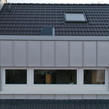 Moderne Dachgaube mit Fenster Graue Metall-Dachgaube mit breiter Fensterfront in Schrägdach integriert.