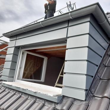 Dachgaube mit Fensterbau Handwerker arbeitet an moderner Gaube mit Metallverkleidung und eingebautem Dachfenster.