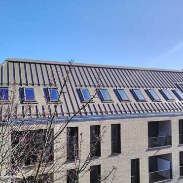 Neubau mit modernem Metalldach Mehrfamilienhaus mit steilem Metalldach und zahlreichen eingebauten Dachfenstern.