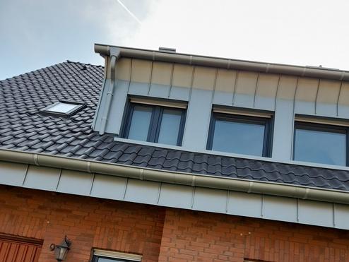 Modernes Wohnhaus mit Dachfenstern und roter Backsteinfassade Ansicht eines zweistöckigen Wohnhauses mit schiefergrauem Ziegeldach, ausgestattet mit Dachfenstern. Die Fassade besteht aus roten Backsteinen, ergänzt durch weiße Fensterrahmen.